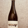 Bottle of wine held by a hand with a textured gray background