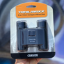 Packaged Carson Trailmaxx 8 x 21mm compact binoculars held against a blurred background.