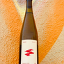 Wine bottle with a red label held against an orange textured background