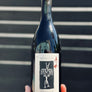 Wine bottle with a unique label held against a striped background