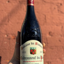 Bottle of Domaine du Banieret Chateauneuf du Pape 2022 held against a brick wall.