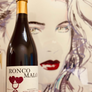 Bottle of Ronco Malo wine held in front of a stylized portrait.