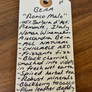 Handwritten tag on a wooden surface with product details.