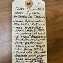 Handwritten tag with wine description on a wooden surface