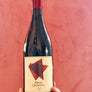 Wine bottle labeled 'Three Quarters' held against a red background
