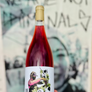 Bottle of Guardian Vital wine held in front of a graffiti-covered wall.