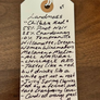 Handwritten tag on a wooden surface with product description