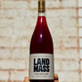 Bottle of Land Mass Chillable Red wine held against a textured wall.