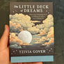Book titled 'The Little Deck of Dreams' by Tzivia Gover held in a hand with a blurred background