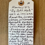Handwritten tag on a wooden surface with product description