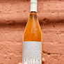 Bottle of rose wine held against a wooden background