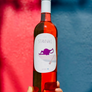 Bottle of red wine with a label held against a colorful background