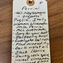 Handwritten tag with wine description on a wooden surface