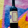 Bottle of Negramaro wine held against a colorful abstract background