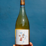 Wine bottle with a label featuring artistic design held against a blue background
