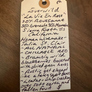 Handwritten tag on a wooden surface with product description text.