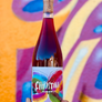 Bottle of Christina Kuhlbart wine held in front of a colorful abstract background