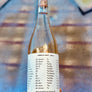Bottle of white wine held by a hand with a blurred background