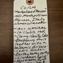Handwritten tag with wine description on a wooden surface