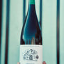 Wine bottle held by a hand with a blue and green striped background