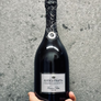 Bottle of Antica Fratta Franciacorta held in a hand against a gray background