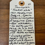 Handwritten tag on a wooden surface with text about wine and flavors.
