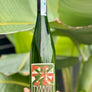 Green wine bottle with decorative label held in front of green leaves