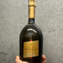 Bottle of Gremillet champagne held by a hand against a gray background
