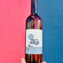Wine bottle held against a red and blue background