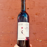 Wine bottle held in front of a red brick wall