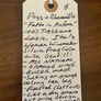 Handwritten tag on a wooden surface with wine description text.