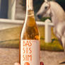 Bottle of Bas Sis Sim wine held in front of a scenic background with a horse.