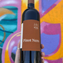 Bottle of Pinot Nero wine held in front of a colorful abstract background