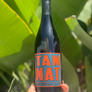 Bottle of Tan Nat wine held in front of green leaves