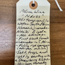 Handwritten tag on a wooden surface with wine information.