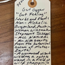 Handwritten tag on a wooden surface with product details.
