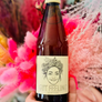 Bottle of 'Gut Feeling' beer held in front of decorative flowers