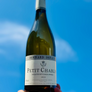 Bottle of Petit Chablis wine held against a blue sky