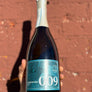 Bottle of Prosecco DOC with a blue label held against a textured brown background