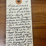 Handwritten tag on a wooden surface with product details.