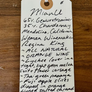 A handwritten recipe tag for MianU wine, detailing ingredients and notes, photographed on a wooden surface.