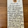 Handwritten tag on a wooden surface with product details.