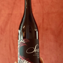Wine bottle with a decorative label held against a red background