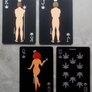 Four playing cards with nude figures and leaf symbols on a textured surface