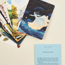 Collection of illustrated cards with a focus on one card featuring a woman in a dress against a starry night sky.