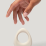 Hand reaching towards a white ceramic object on a light gray background