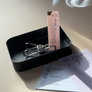 Black tin with a hair clip and pink ribbon labeled 'I choose positivity' on a light surface.