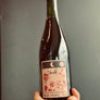 Bottle of wine held by a hand with a label on a gray background