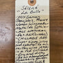 Handwritten tag on a wooden surface with product details.