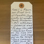 Handwritten label with wine information on a wooden surface